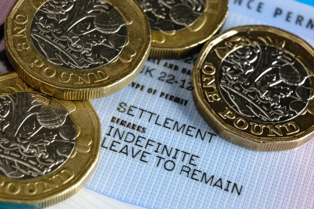 Close up of an indefinite leave to remain residence permit with British pound coins on top